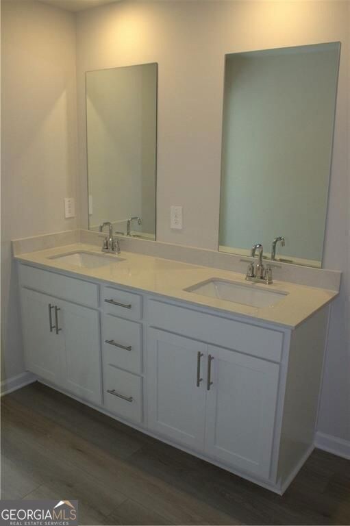 Bathroom with double vanity and wood finished floors