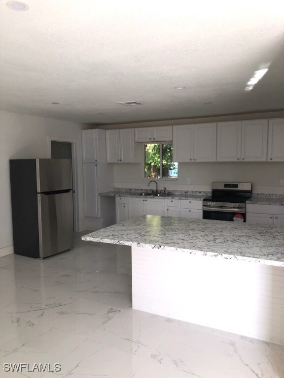 Kitchen with light stone countertops, white cabine