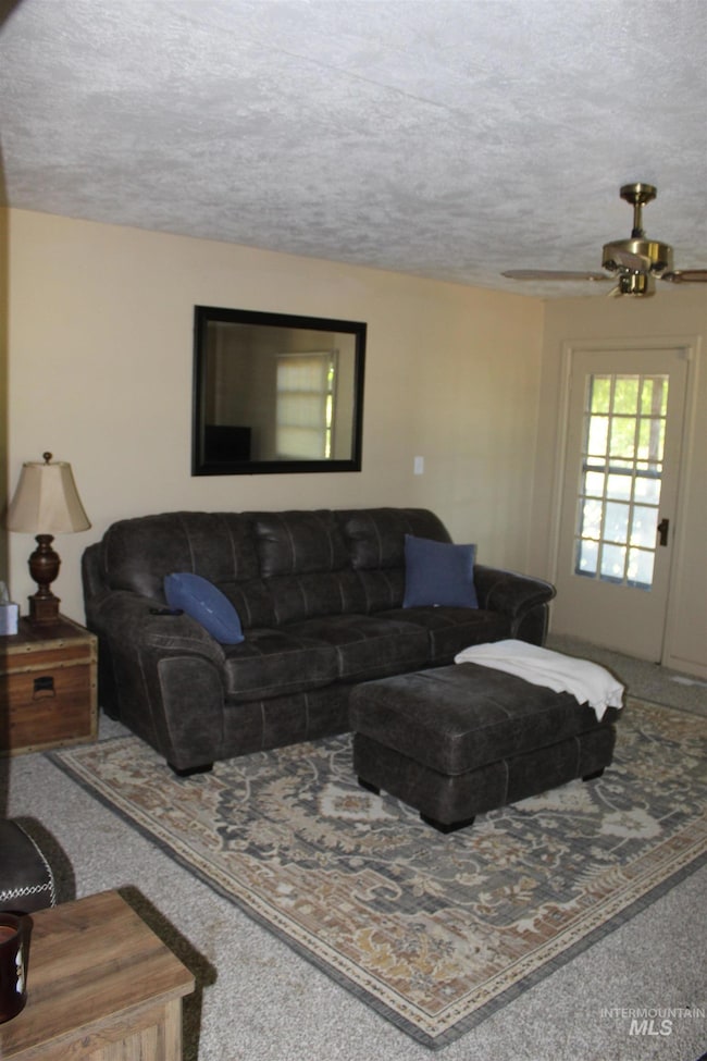 Living room with carpet floors, a textured ceiling, and ceiling fan