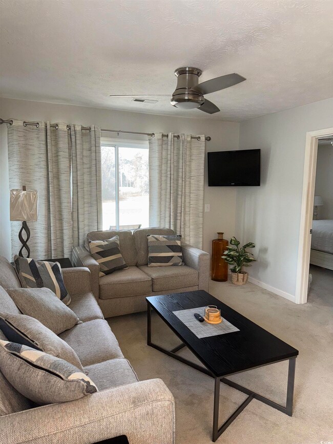 Living room featuring a textured ceiling, light carpet, and ceiling fan