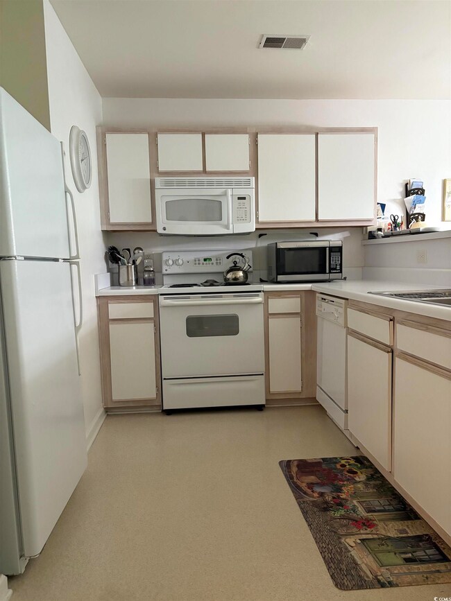 Kitchen with white cabinets, visible vents, light 