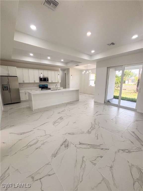 Unfurnished living room with a tray ceiling, a cha