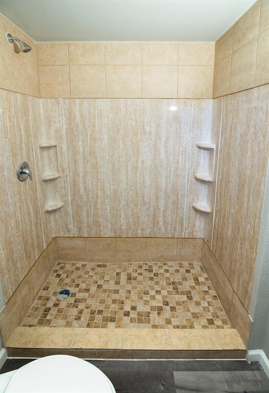 Full bath featuring a shower stall and toilet