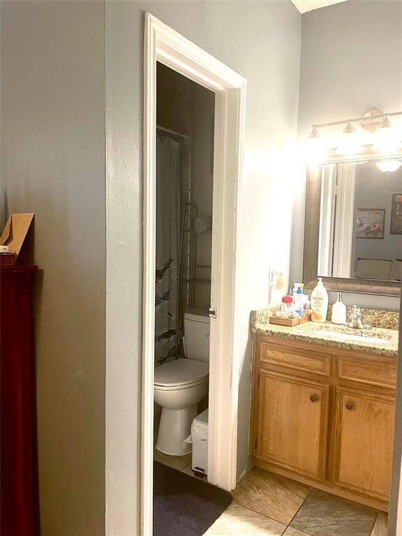 Full bath featuring toilet, vanity, and tile patt
