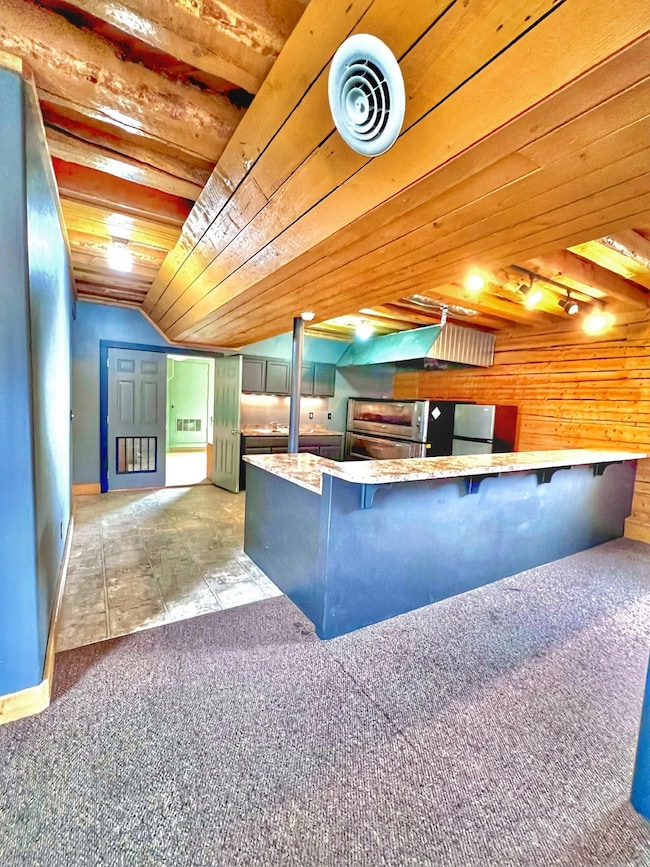 Kitchen featuring wood ceiling, a kitchen bar, lofted ceiling, carpet flooring, and a peninsula