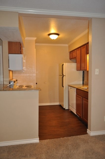 Kitchen with brown cabinetry, dark carpet, dishwas