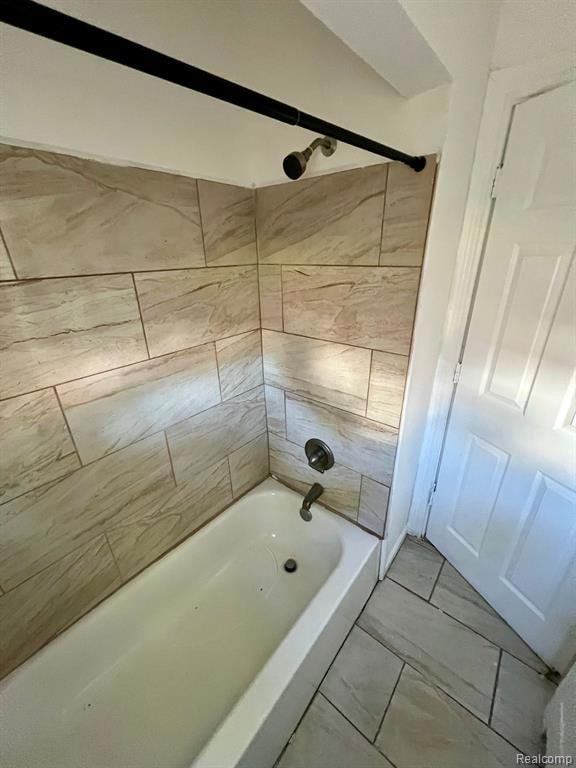 Bathroom with bathtub / shower combination and light marble finish flooring