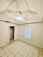 Unfurnished bedroom featuring a closet, baseboards, light tile patterned floors, and ceiling fan