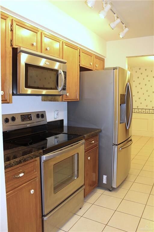 Kitchen with light tile patterned floors, stainless steel appliances, and dark stone counters