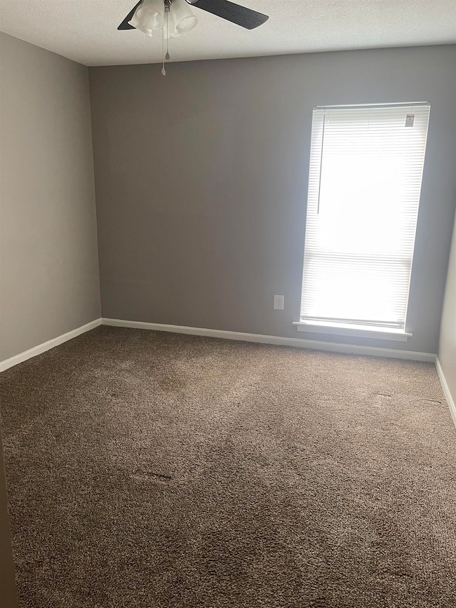 Empty room featuring ceiling fan, carpet, baseboar