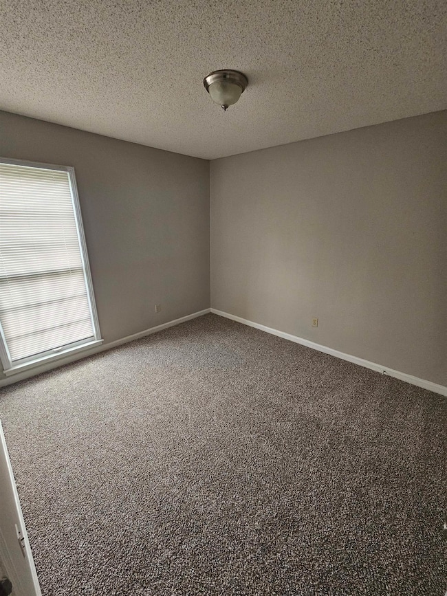 Carpeted empty room with baseboards and a textured ceiling
