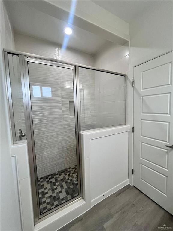 Bathroom featuring a shower with door and hardwood / wood-style flooring