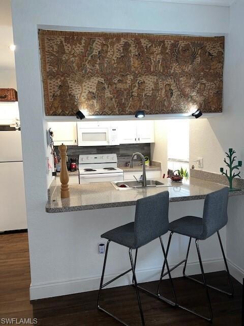 Kitchen with stove, a peninsula, refrigerator, and a sink