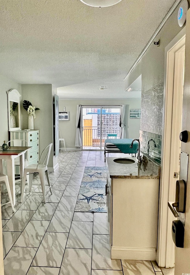Kitchen with a textured ceiling, dark stone counters, decorative backsplash, a peninsula, and light marble finish floors