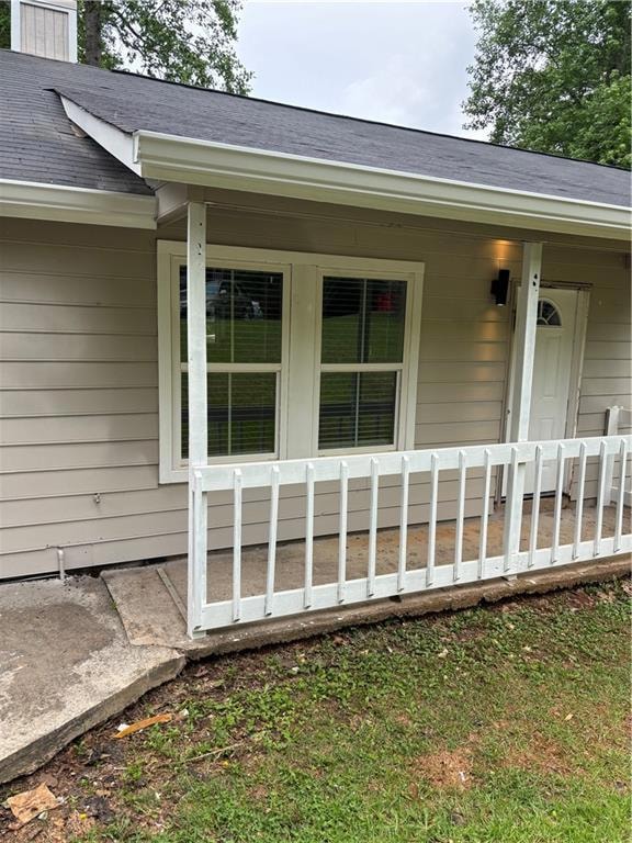 Property entrance with roof with shingles and a porch