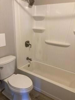 Bathroom with toilet, hardwood / wood-style floors, and shower / bathing tub combination