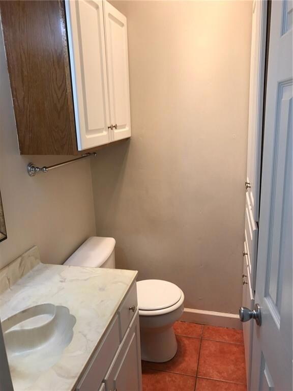 Bathroom with baseboards, vanity, toilet, and til