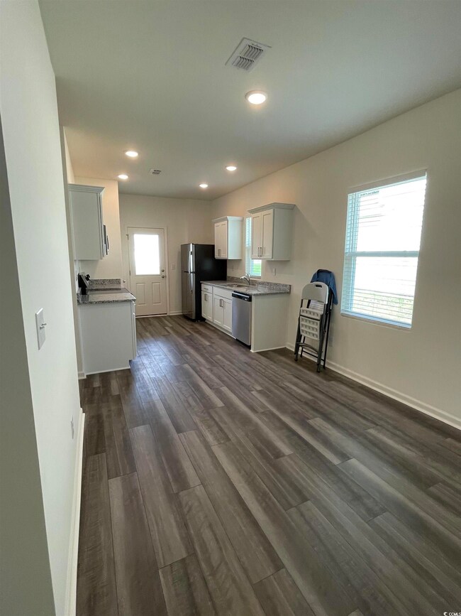Kitchen featuring appliances with stainless steel finishes, dark wood-type flooring, recessed lighting, light countertops, and white cabinetry