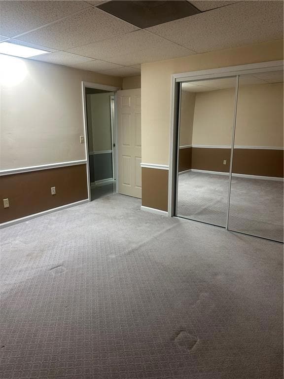 Unfurnished bedroom with a closet, carpet flooring, and a drop ceiling