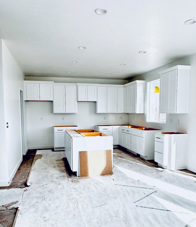 Kitchen featuring a center island, white cabinets, and concrete floors