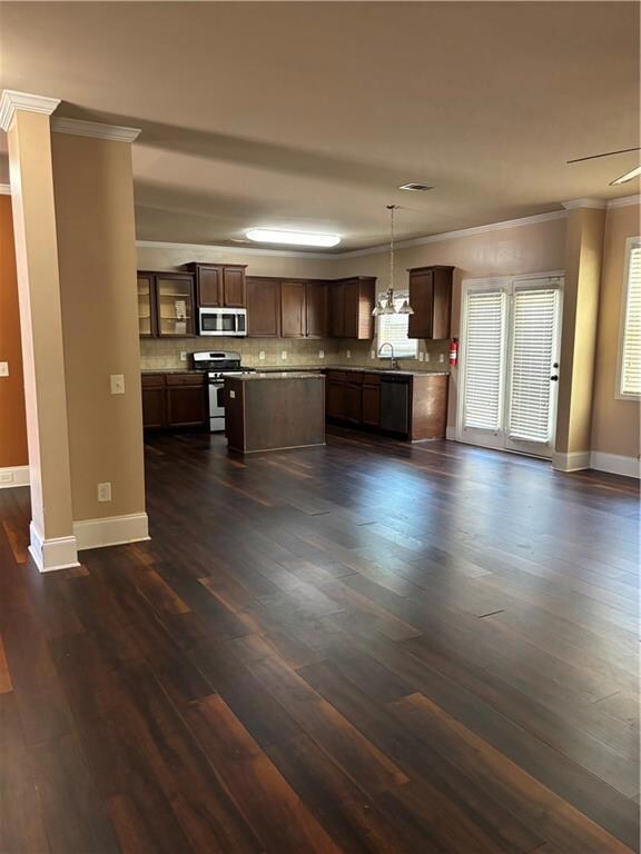Kitchen featuring crown molding, glass insert cabinets, tasteful backsplash, dark brown cabinets, and range