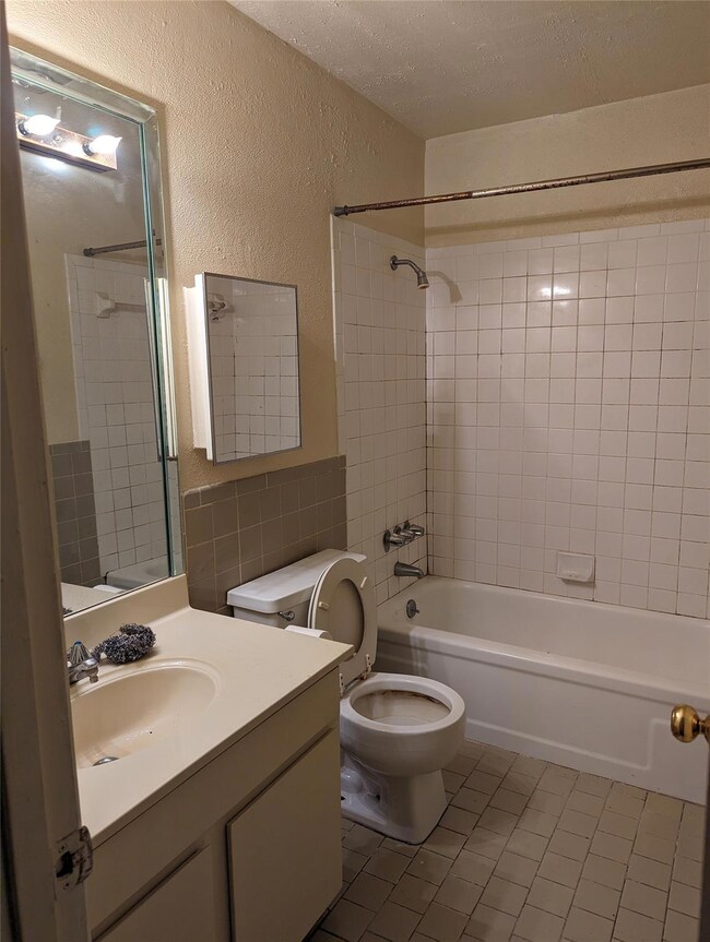 Full bathroom with a textured ceiling, tile floors
