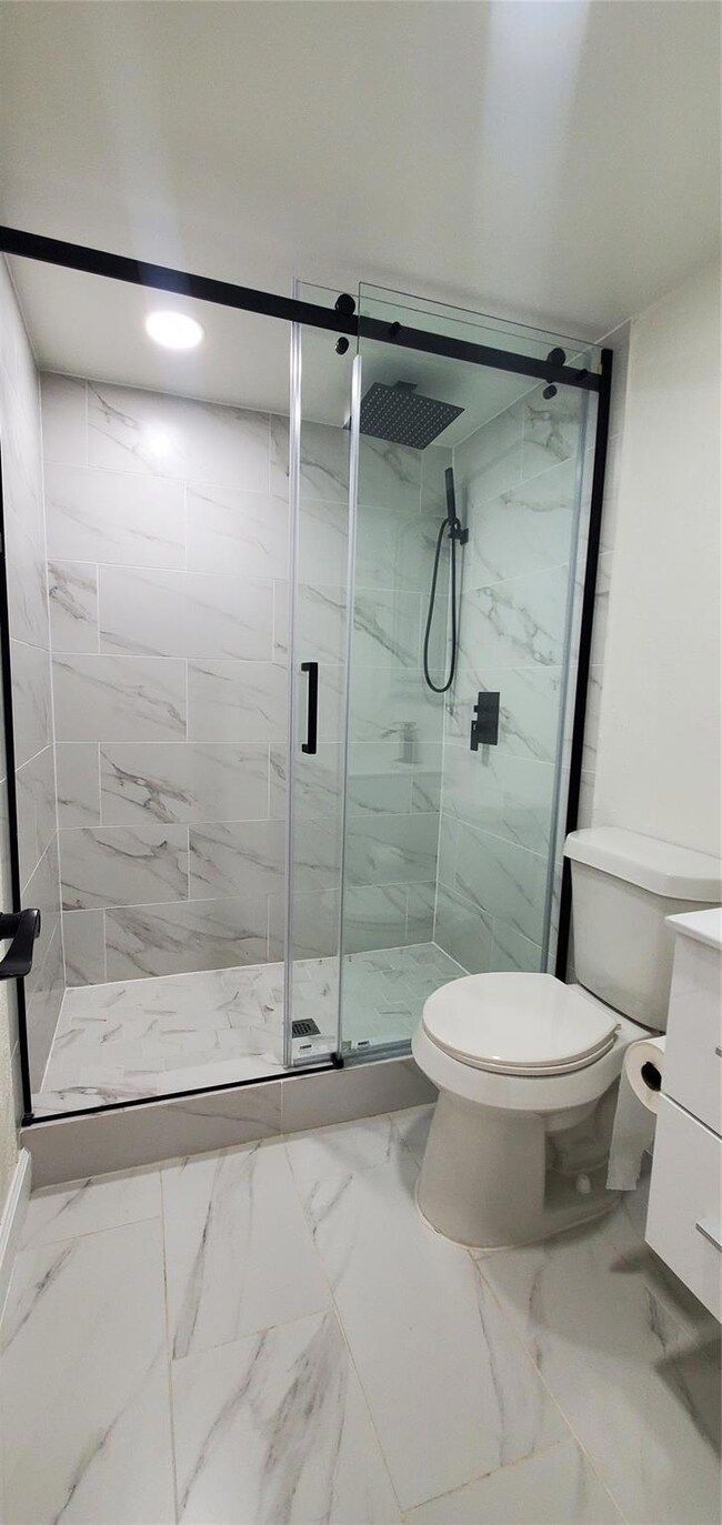 Bathroom featuring toilet, vanity, and a shower wi