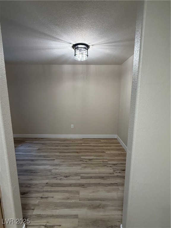 Spare room featuring baseboards, a textured ceiling, and wood finished floors