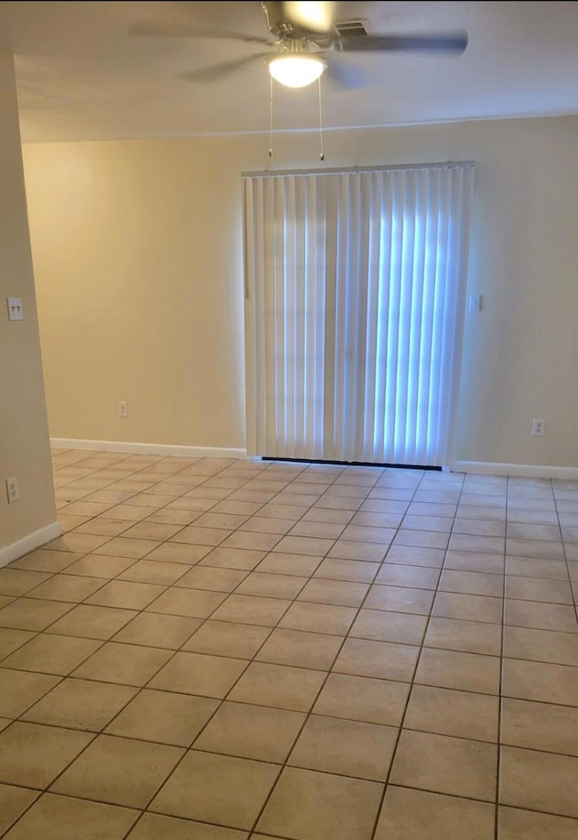 Spare room featuring light tile patterned floors, baseboards, and ceiling fan