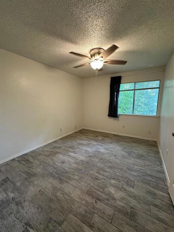 Unfurnished room featuring a textured ceiling, dark wood finished floors, and ceiling fan