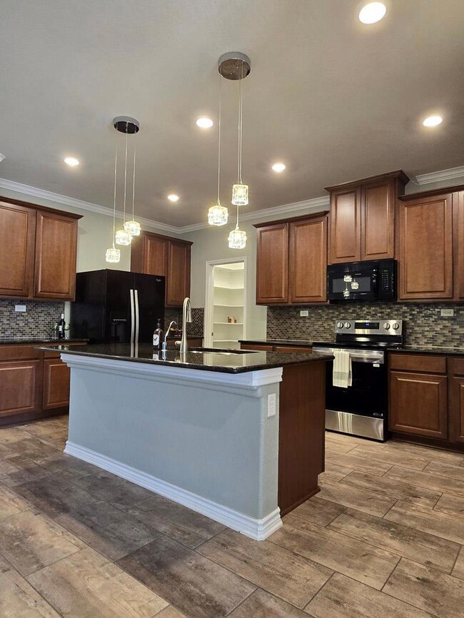 Kitchen with hanging light fixtures, black applia