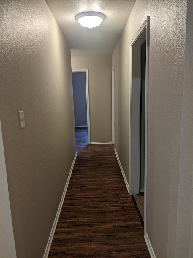 Corridor featuring dark wood-type flooring