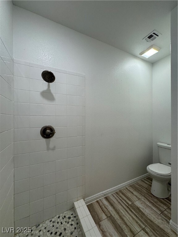 Bathroom featuring a tile shower, wood finished fl