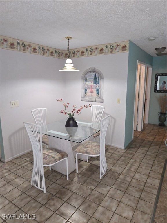 Dining area with a textured ceiling and light tile