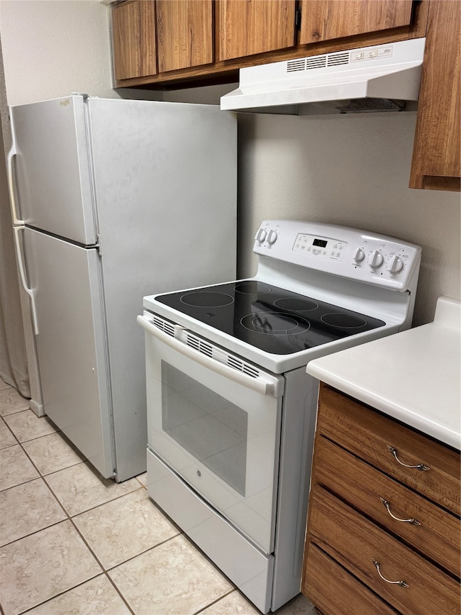Includes refrigerator, electric range, and vent hood. The practical layout offers plenty of storage and tile flooring for easy maintenance.
