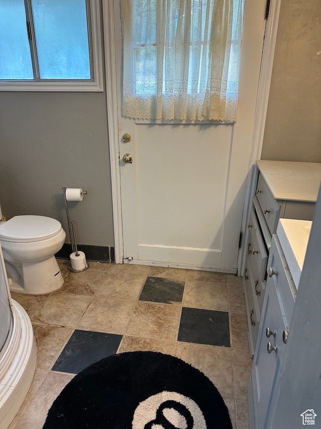 3/4 bathroom with toilet and baseboards