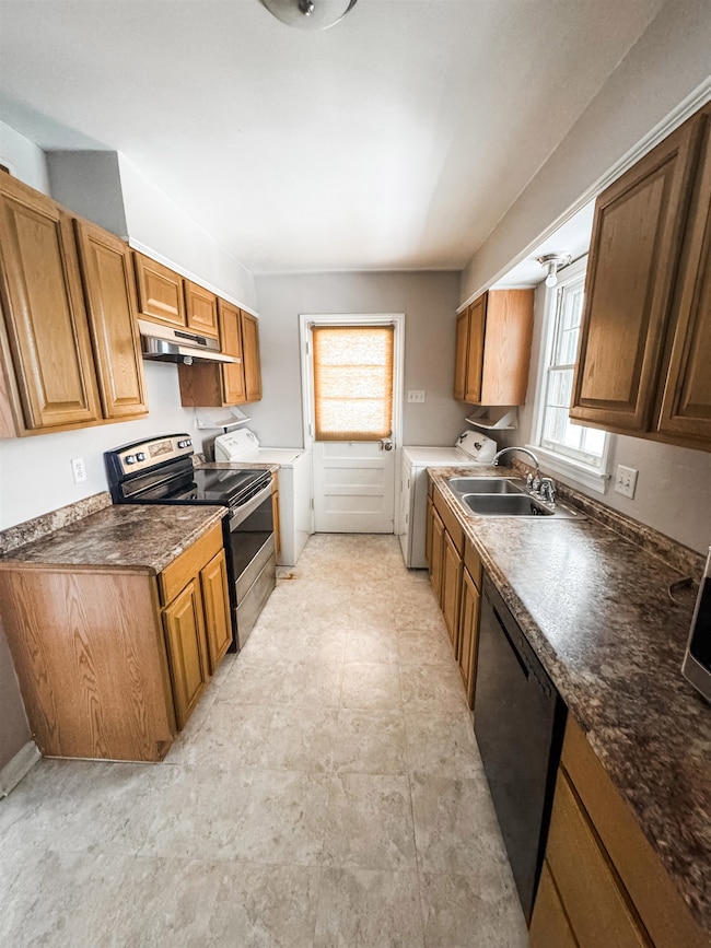 Kitchen with stainless steel range with electric stovetop, dark countertops, black dishwasher, and brown cabinets