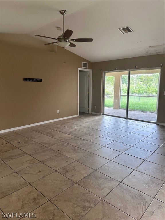 Tiled empty room with lofted ceiling and ceiling f