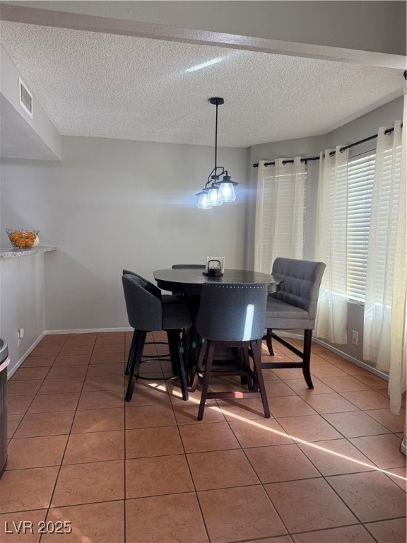 Dining space featuring light tile patterned floors and a textured ceiling