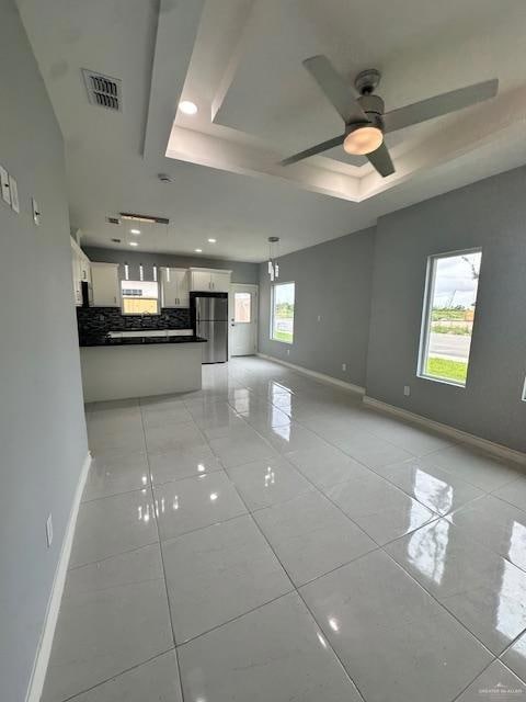 Unfurnished living room featuring a raised ceiling, light tile patterned floors, ceiling fan, and recessed lighting