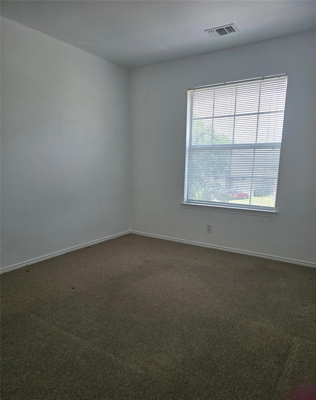 Carpeted spare room featuring baseboards