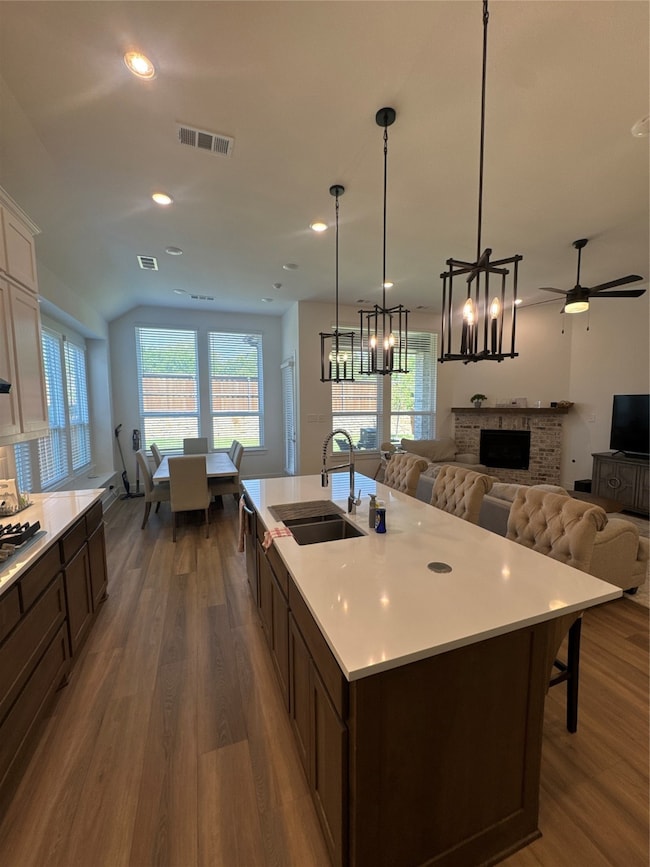 Kitchen featuring open floor plan, dark brown cabinetry, dark wood-type flooring, recessed lighting, and pendant lighting