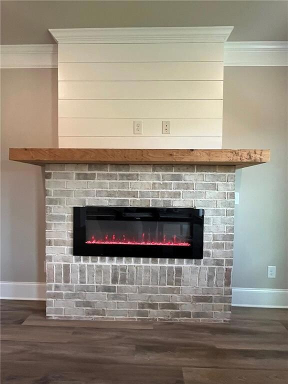 Detailed view of ornamental molding, a fireplace, and wood finished floors