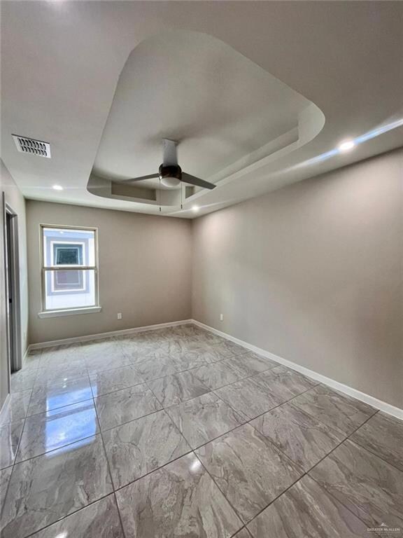 Unfurnished room with ceiling fan and a raised ceiling