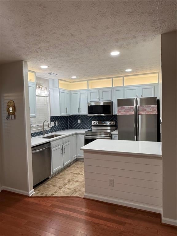 Kitchen with fridge, backsplash, a textured ceiling, range, and dishwasher
