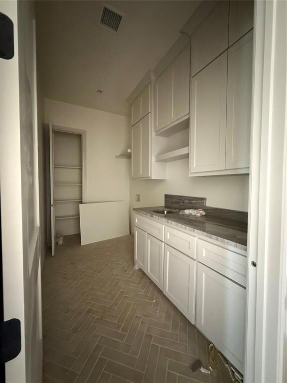 Kitchen with visible vents, white cabinetry, and o