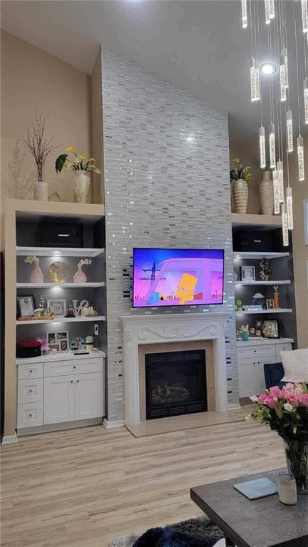 Living area with a high end fireplace, light wood finished floors, and built in shelves