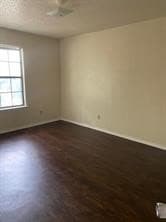 Unfurnished room with dark wood-style floors and baseboards