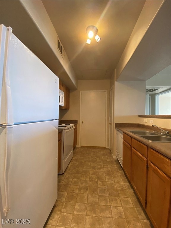 Kitchen featuring stainless steel refrigerator, brown cabinetry, white range oven, and dishwashing machine