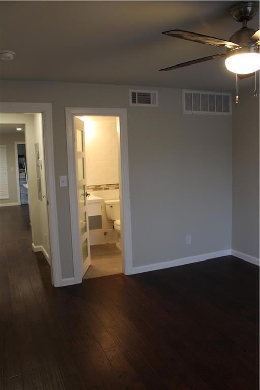 Empty room featuring ceiling fan, dark wood-type 